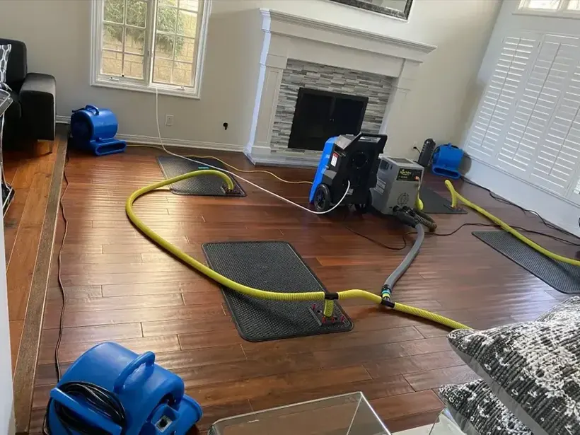 Air mover and extraction hose drying a flooded Bay Shore living-room floor